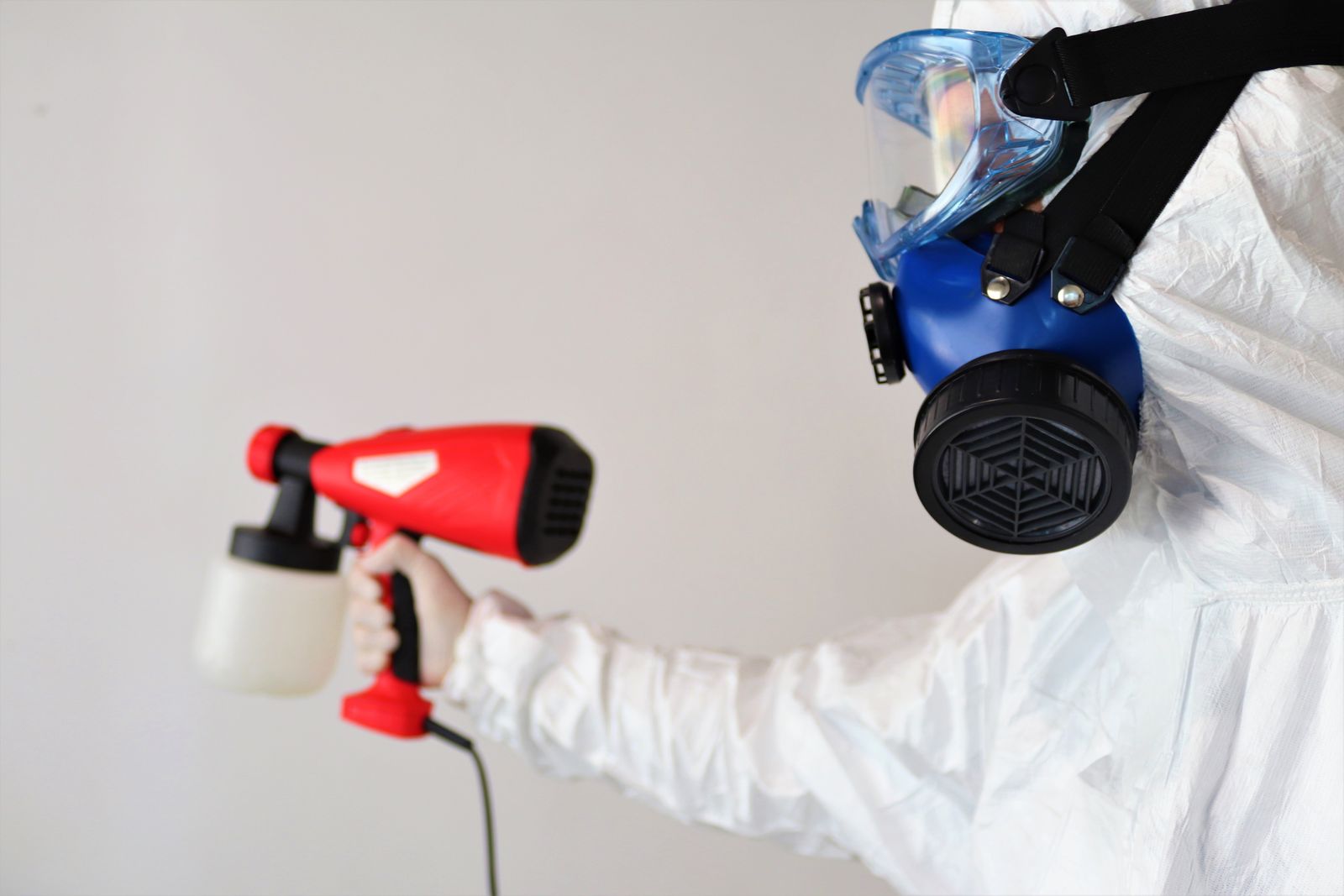 Technician in protective gear and respirator working indoors